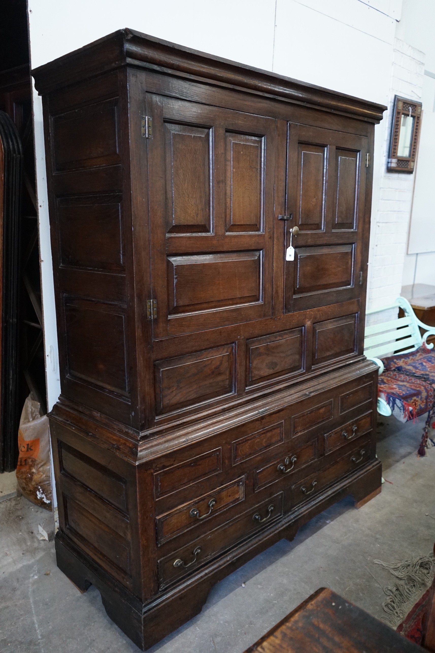 An 18th century panelled oak press cupboard, width 140cm, depth 56cm, height 185cm